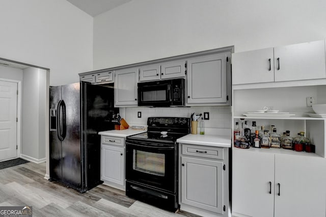 kitchen featuring tasteful backsplash, gray cabinets, light hardwood / wood-style flooring, and black appliances