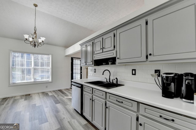 kitchen with decorative backsplash, light wood-type flooring, sink, dishwasher, and a chandelier