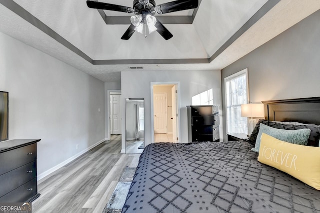 bedroom with a raised ceiling, ceiling fan, and wood-type flooring