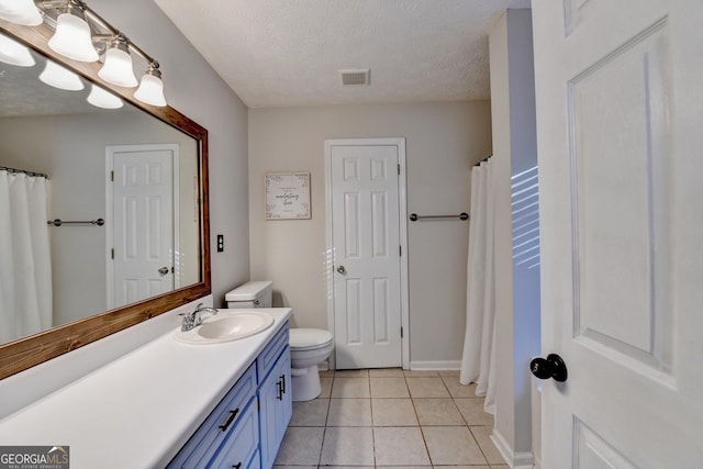 bathroom with tile patterned floors, vanity, a textured ceiling, and toilet