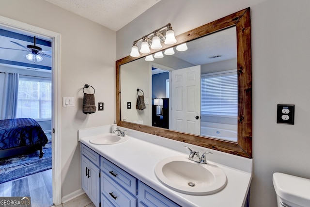 bathroom with vanity, a textured ceiling, ceiling fan, hardwood / wood-style flooring, and toilet