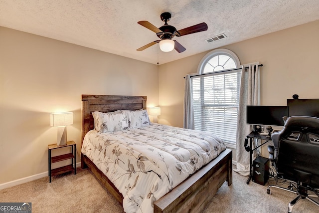 bedroom featuring ceiling fan, light colored carpet, and a textured ceiling