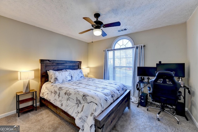 bedroom with a textured ceiling, light colored carpet, and ceiling fan