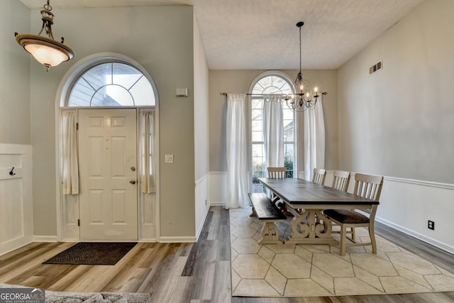 entrance foyer featuring a wealth of natural light, hardwood / wood-style floors, a textured ceiling, and an inviting chandelier