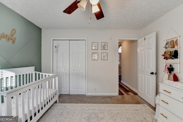 bedroom with ceiling fan, a textured ceiling, light carpet, and a closet