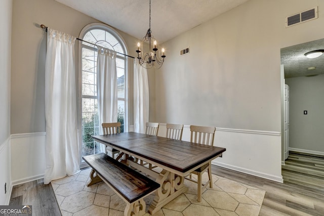 dining room featuring a chandelier, a textured ceiling, light hardwood / wood-style floors, and a healthy amount of sunlight