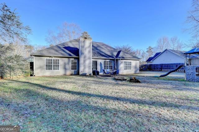 rear view of property featuring a yard and a playground