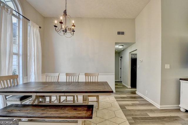 dining space with a textured ceiling, light hardwood / wood-style floors, an inviting chandelier, and a wealth of natural light