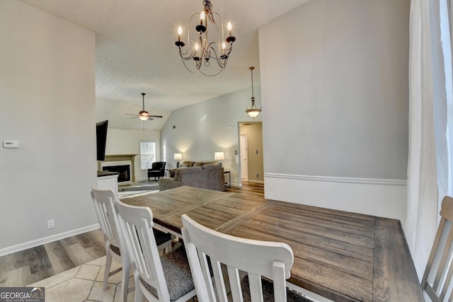 dining room with light hardwood / wood-style flooring, ceiling fan with notable chandelier, and vaulted ceiling