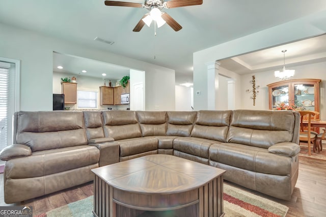 living room featuring light hardwood / wood-style floors and ceiling fan with notable chandelier