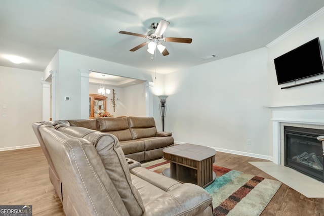 living room featuring crown molding, light hardwood / wood-style floors, and ceiling fan with notable chandelier