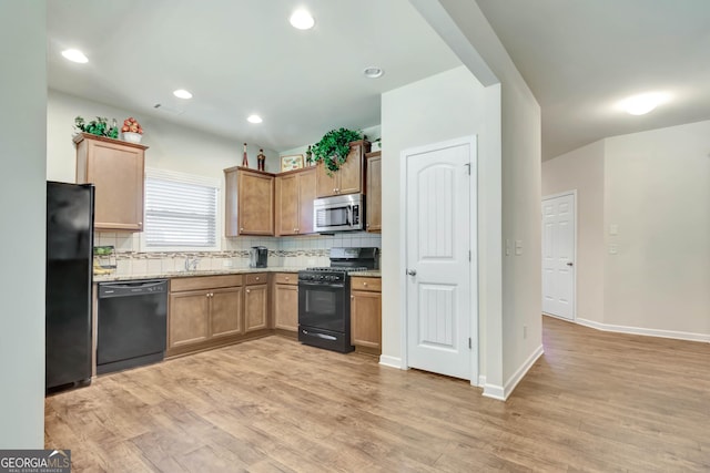 kitchen featuring decorative backsplash, light stone counters, sink, black appliances, and light hardwood / wood-style flooring