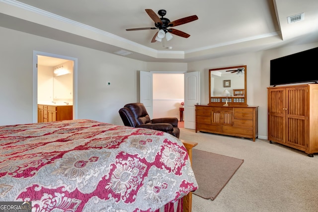 carpeted bedroom featuring a tray ceiling, ensuite bath, ceiling fan, and crown molding