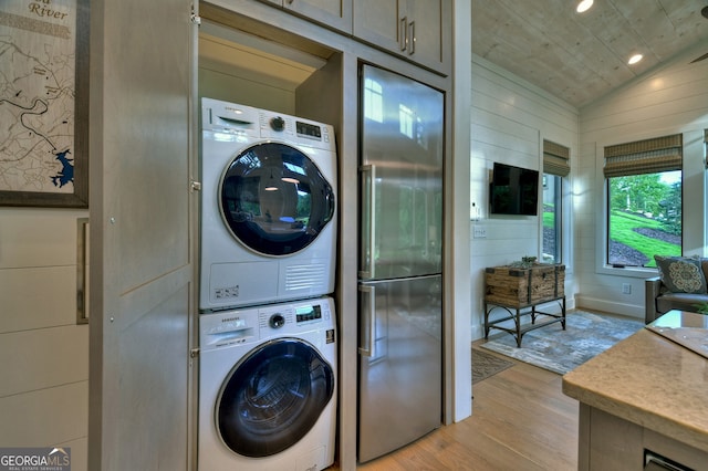 washroom with light hardwood / wood-style flooring and stacked washer and clothes dryer