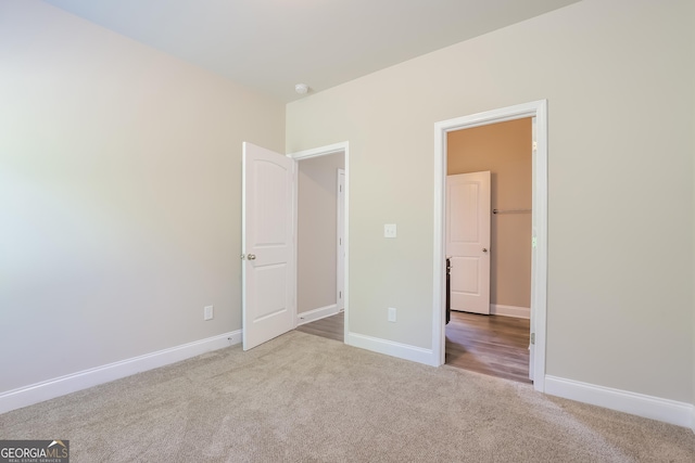 unfurnished bedroom featuring a spacious closet and light colored carpet