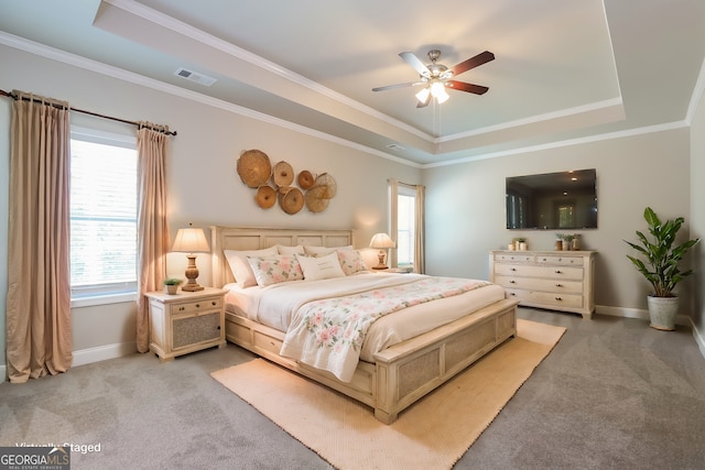 bedroom featuring ceiling fan, light colored carpet, crown molding, and a tray ceiling