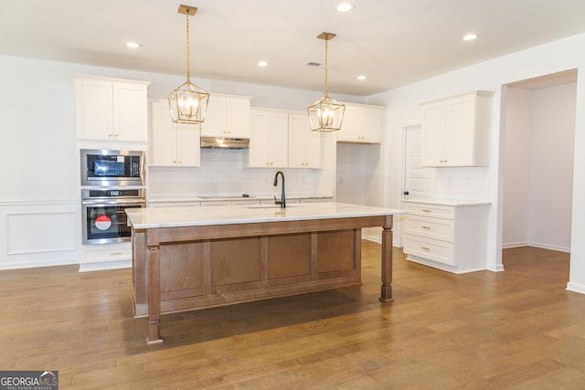 kitchen featuring light countertops, under cabinet range hood, a sink, white cabinets, and appliances with stainless steel finishes