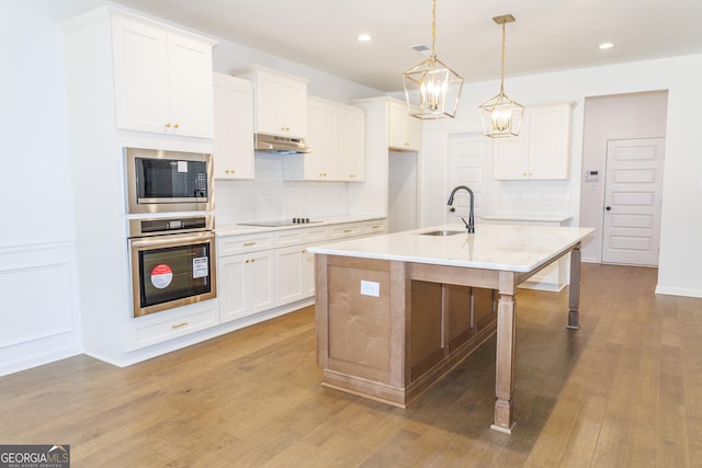 kitchen with black electric cooktop, oven, under cabinet range hood, a sink, and built in microwave