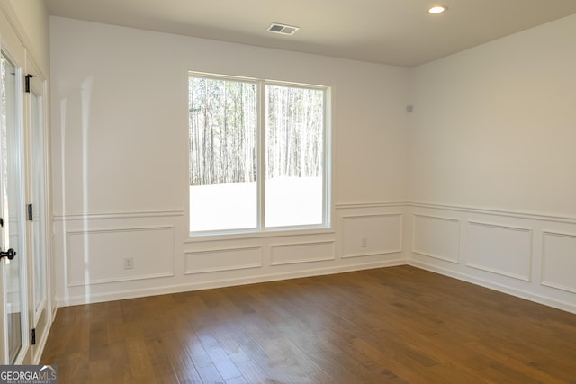 unfurnished room with visible vents, a decorative wall, recessed lighting, and dark wood-style flooring