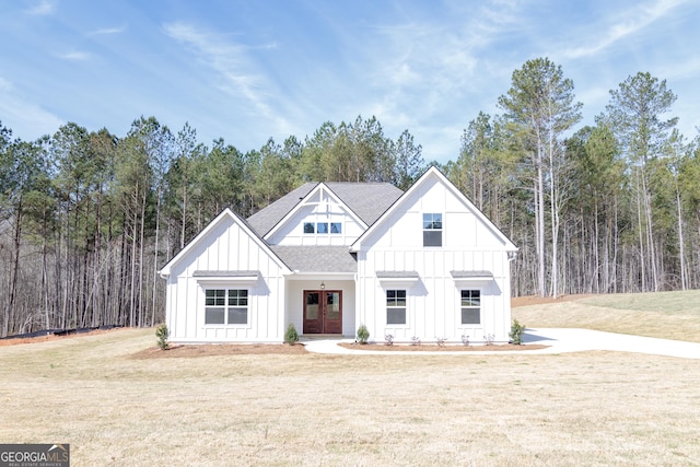 view of front facade with french doors, board and batten siding, roof with shingles, and a front lawn