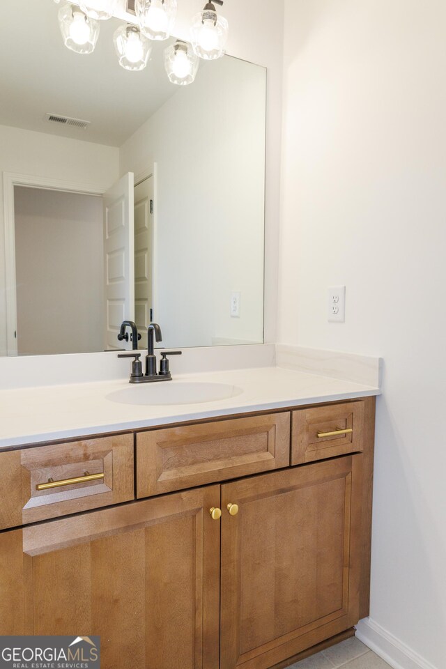 bathroom with an inviting chandelier, vanity, baseboards, and visible vents
