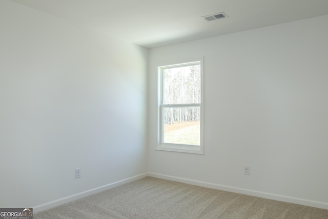 spare room with baseboards, light colored carpet, visible vents, and plenty of natural light