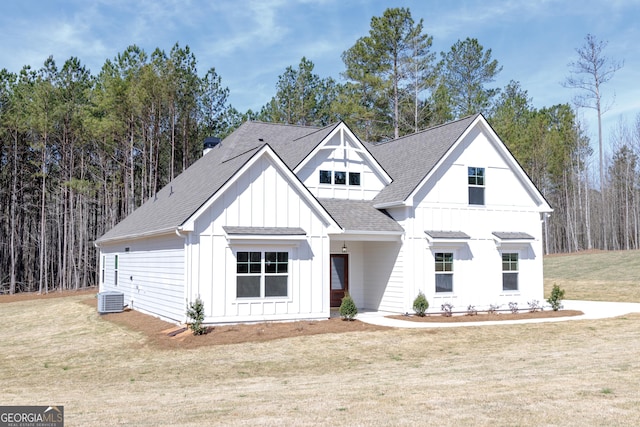 modern farmhouse featuring central air condition unit, roof with shingles, board and batten siding, and a front yard