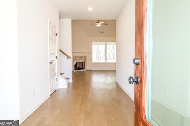hallway with baseboards, visible vents, light wood-style floors, and stairway