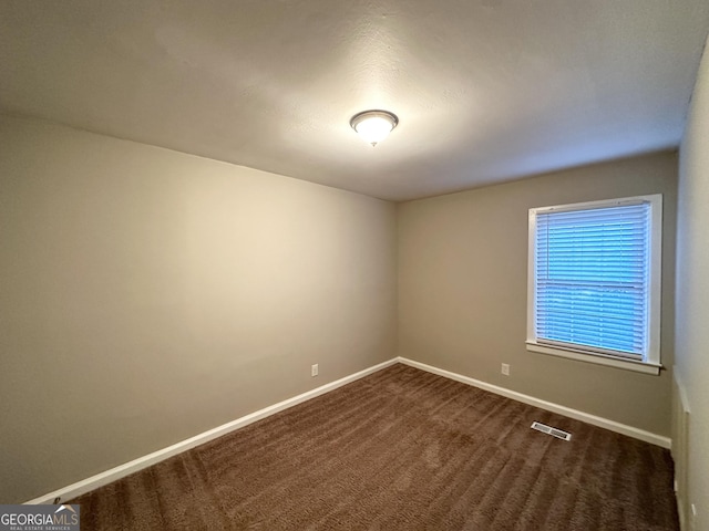 spare room featuring dark carpet