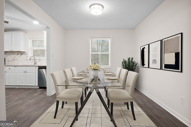 dining space featuring light wood-type flooring and a textured ceiling