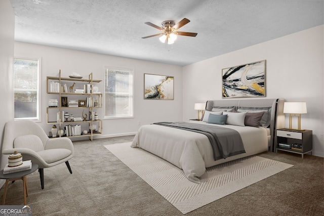 carpeted bedroom featuring ceiling fan and a textured ceiling