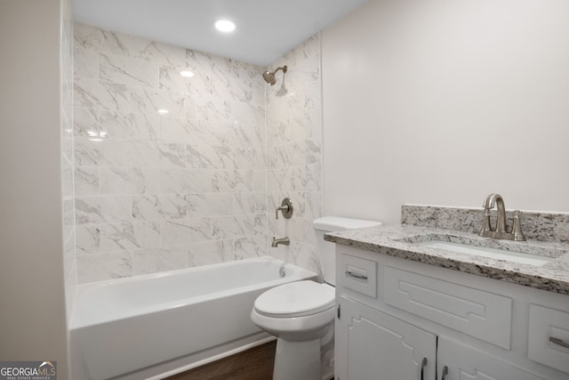 full bathroom featuring hardwood / wood-style floors, vanity, toilet, and tiled shower / bath combo