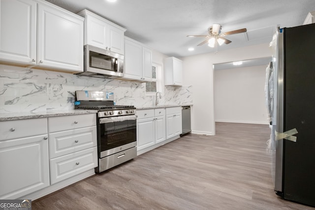 kitchen featuring backsplash, stainless steel appliances, sink, light hardwood / wood-style flooring, and white cabinets