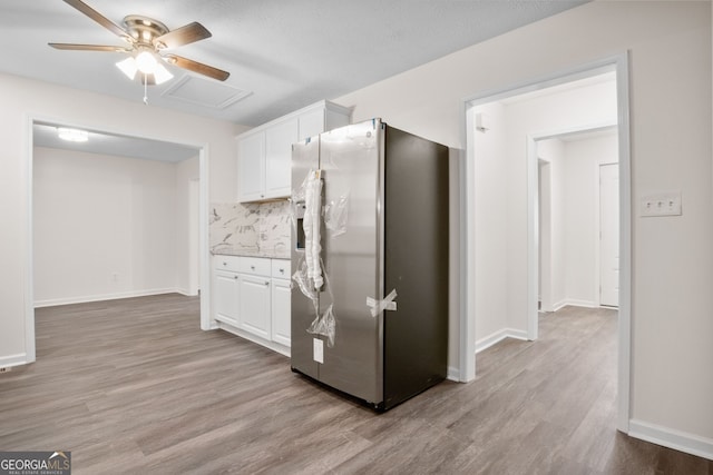 kitchen featuring decorative backsplash, stainless steel fridge, ceiling fan, light hardwood / wood-style flooring, and white cabinets