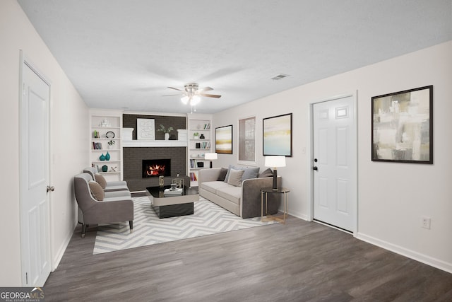 living room with ceiling fan, a fireplace, a textured ceiling, and hardwood / wood-style flooring