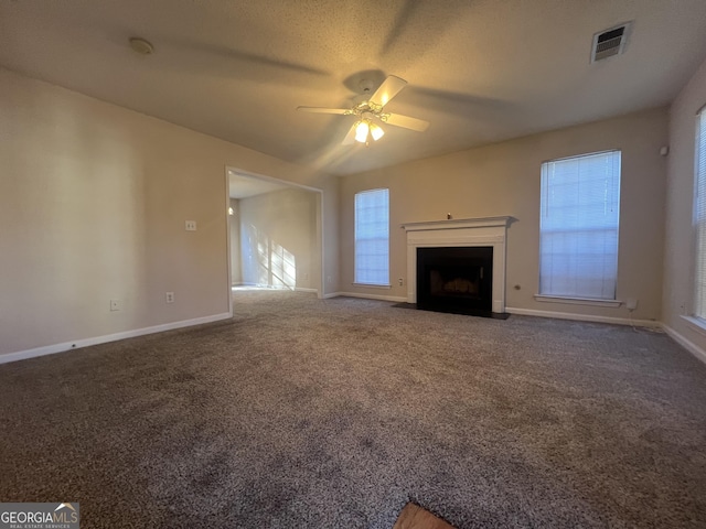 unfurnished living room featuring ceiling fan, a textured ceiling, carpet, and a wealth of natural light