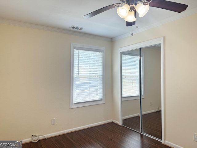 unfurnished bedroom featuring ceiling fan, a closet, crown molding, and dark hardwood / wood-style floors