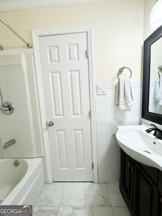 bathroom featuring vanity, washtub / shower combination, and tile walls