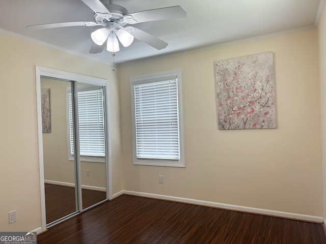 unfurnished bedroom featuring ceiling fan, dark hardwood / wood-style flooring, ornamental molding, and a closet