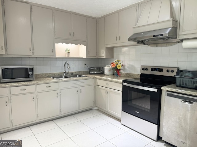 kitchen with sink, stainless steel appliances, wall chimney range hood, backsplash, and light tile patterned floors