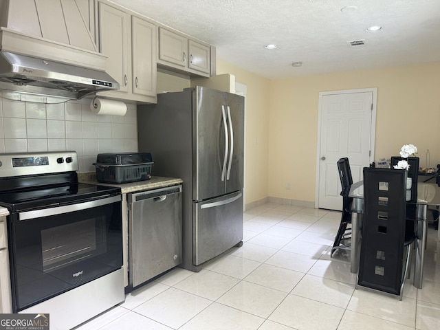 kitchen with decorative backsplash, light tile patterned floors, extractor fan, and appliances with stainless steel finishes