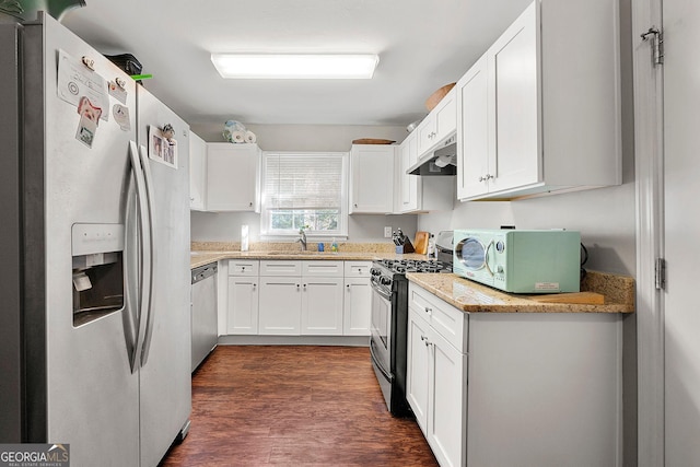 kitchen with sink, dark hardwood / wood-style floors, light stone countertops, appliances with stainless steel finishes, and white cabinetry