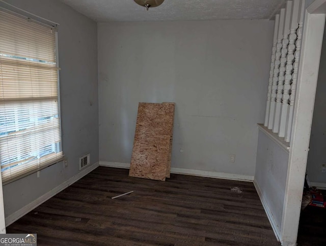 unfurnished room with dark hardwood / wood-style flooring and a textured ceiling