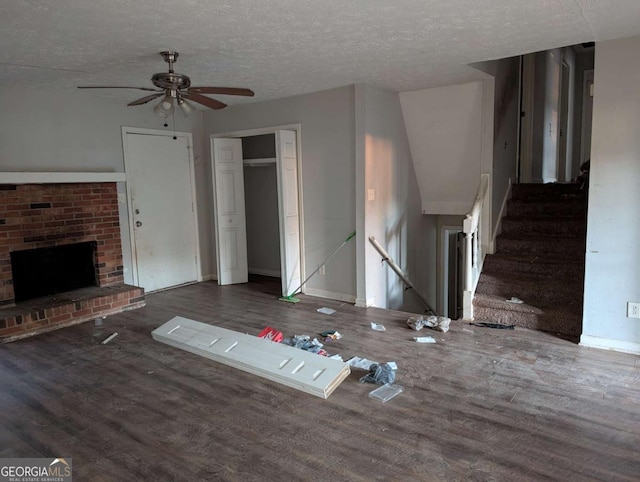 unfurnished living room with a fireplace, ceiling fan, dark hardwood / wood-style flooring, and a textured ceiling