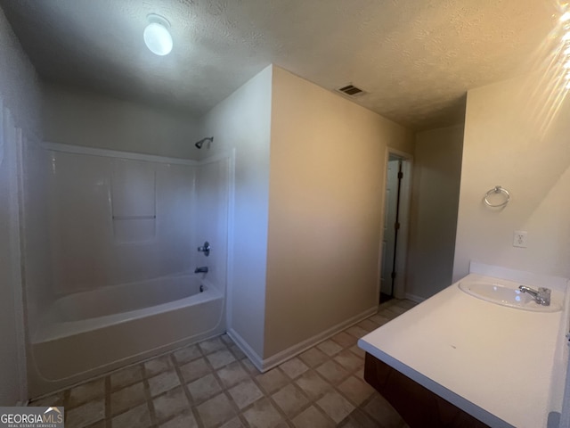 bathroom with a textured ceiling, shower / bathing tub combination, a sink, and visible vents