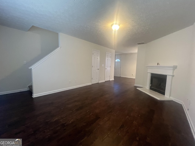 unfurnished living room with a textured ceiling and dark hardwood / wood-style floors