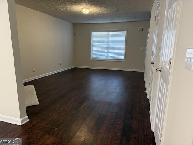 spare room featuring dark wood finished floors, a textured ceiling, and baseboards