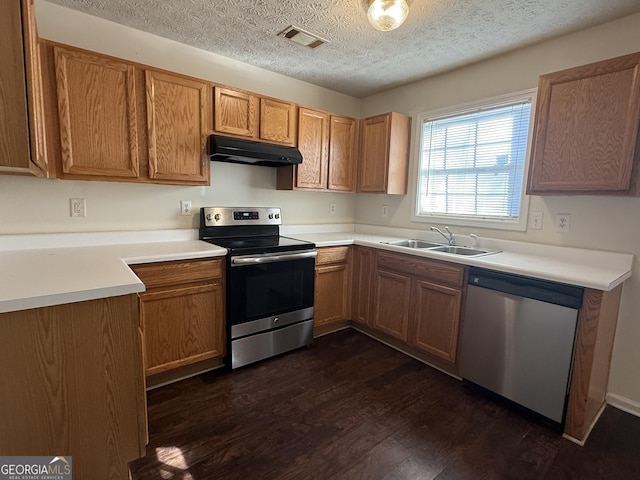 kitchen featuring dark wood-style floors, stainless steel appliances, a sink, a textured ceiling, and under cabinet range hood