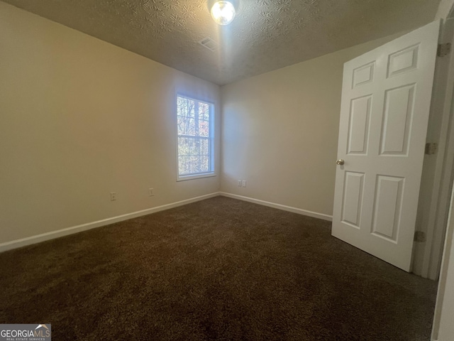 empty room with baseboards, dark colored carpet, and a textured ceiling