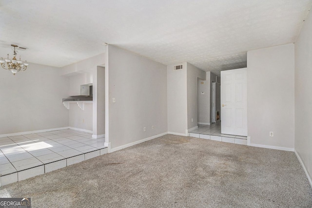 unfurnished living room with light carpet, baseboards, visible vents, a textured ceiling, and a chandelier